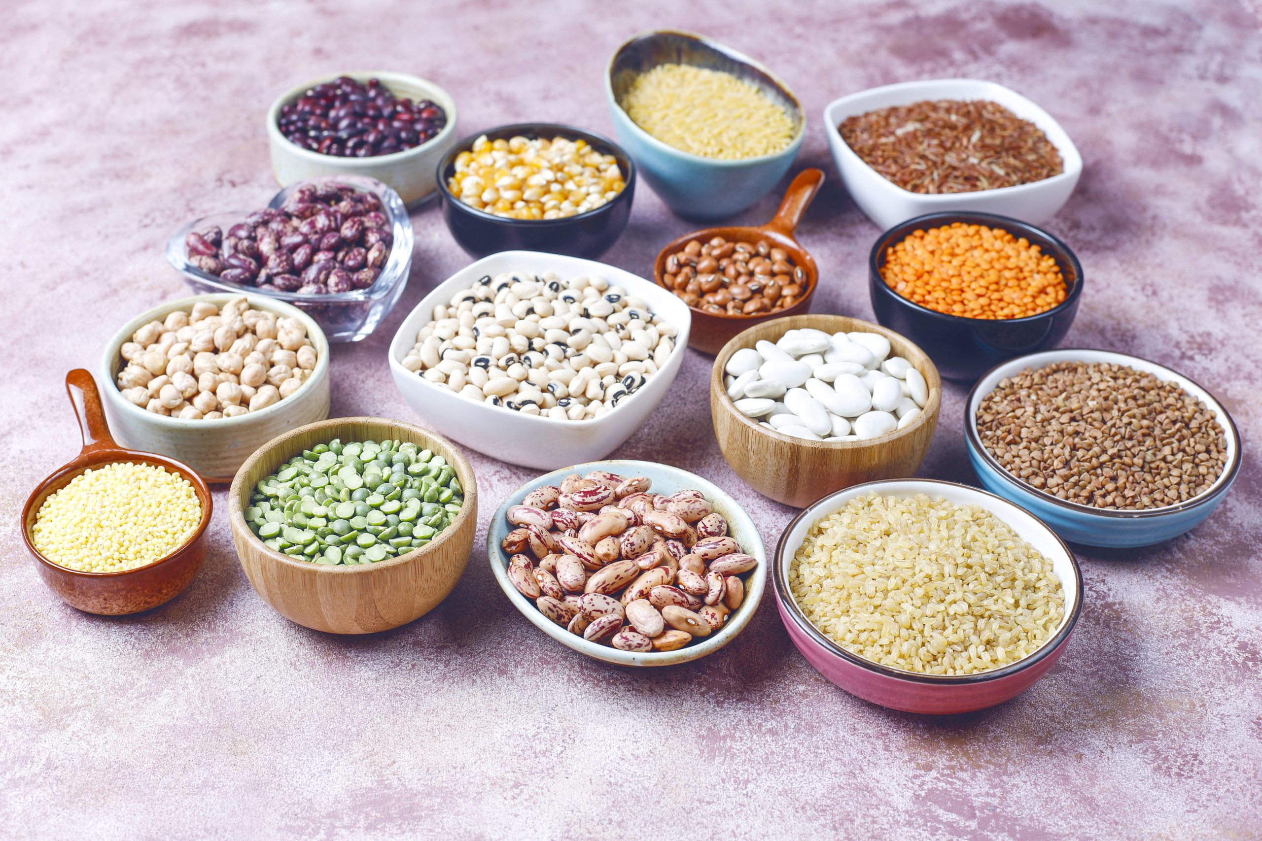 legumes and beans assortment in different bowls on light stone b